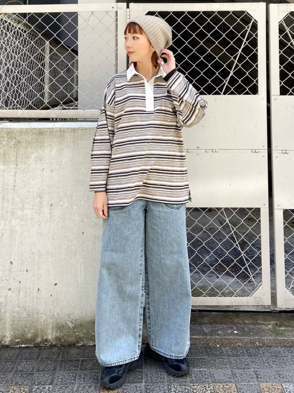 ベージュ系のポロシャツ、ブルー系のデニムパンツを着用したレディースの冬コーディネートの1枚目の写真