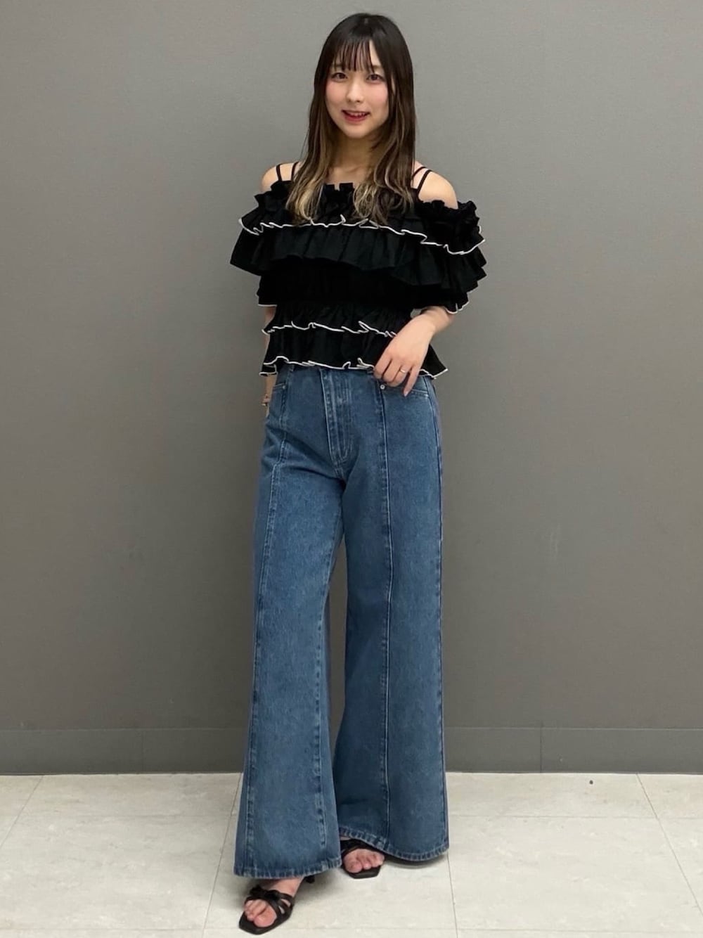 ブルー系のデニムパンツ、ブラック系のサンダル、ブラック系のシャツ/ブラウスを着用したレディースの夏コーディネートの1枚目の写真