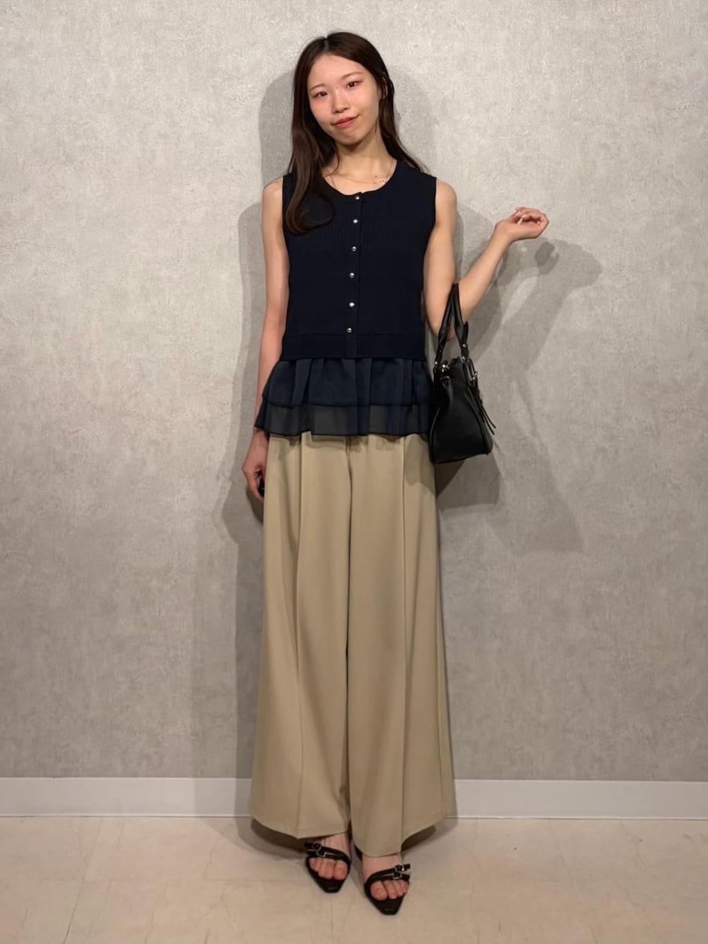 ブルー系のニット/セーター、ブラック系のショルダーバッグ、ブラック系のサンダルを着用したレディースの夏コーディネートの1枚目の写真