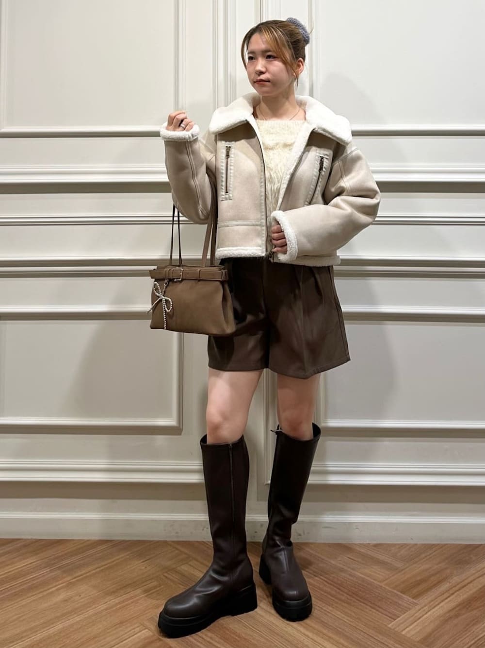 ホワイト系のムートンコートを着用したレディースの秋コーディネートの1枚目の写真