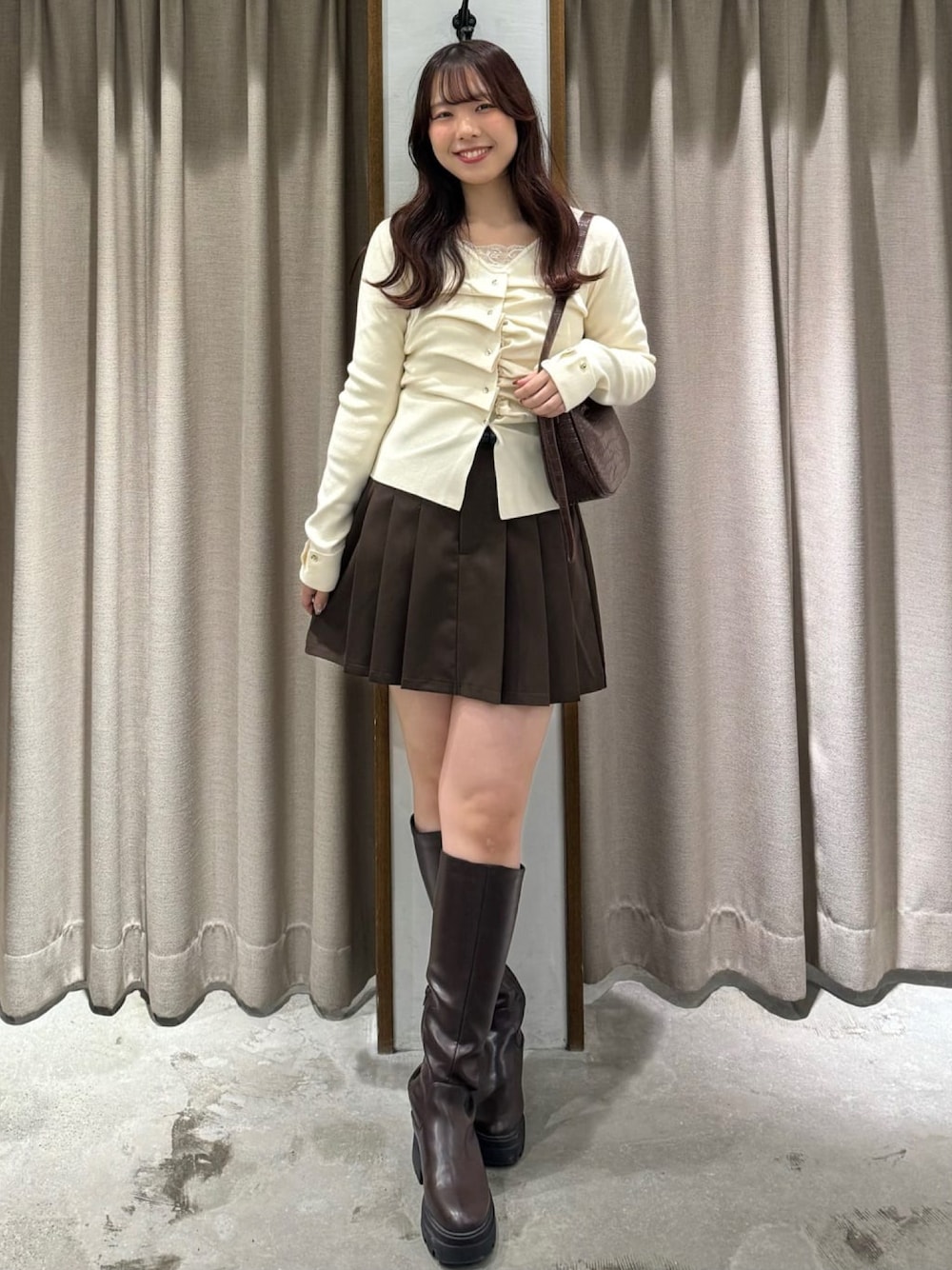 ホワイト系のニット/セーター、ブラウン系のスカートを着用したレディースの冬コーディネートの1枚目の写真