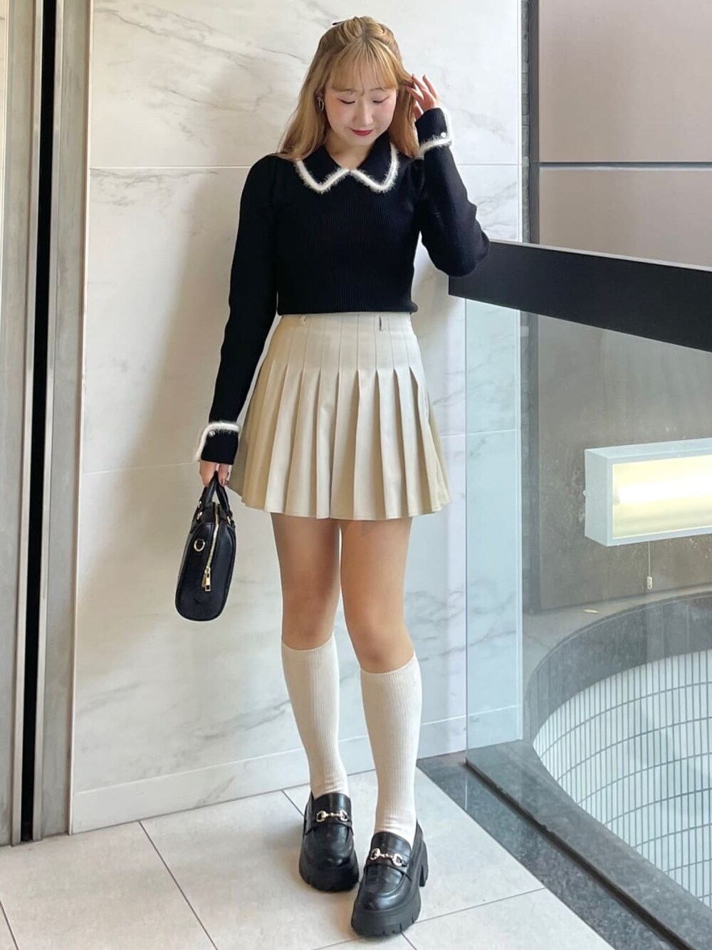 ブラック系のニット/セーター、ホワイト系のスカート、ブラック系のボストンバッグを着用したレディースの冬コーディネートの1枚目の写真