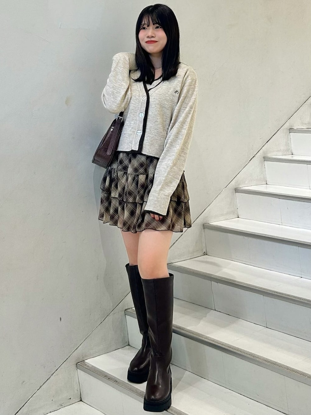 ブラウン系のアンサンブル、ブルー系のスカートを着用したレディースの秋コーディネートの1枚目の写真