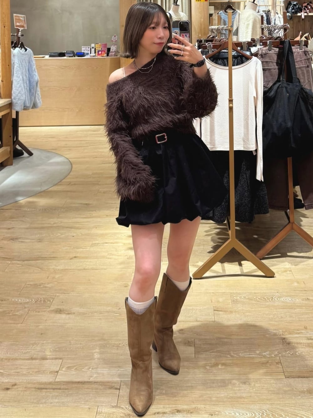 ブラウン系のニット/セーター、ブラック系のスカート、イエロー系のブーツを着用したレディースの秋コーディネートの1枚目の写真