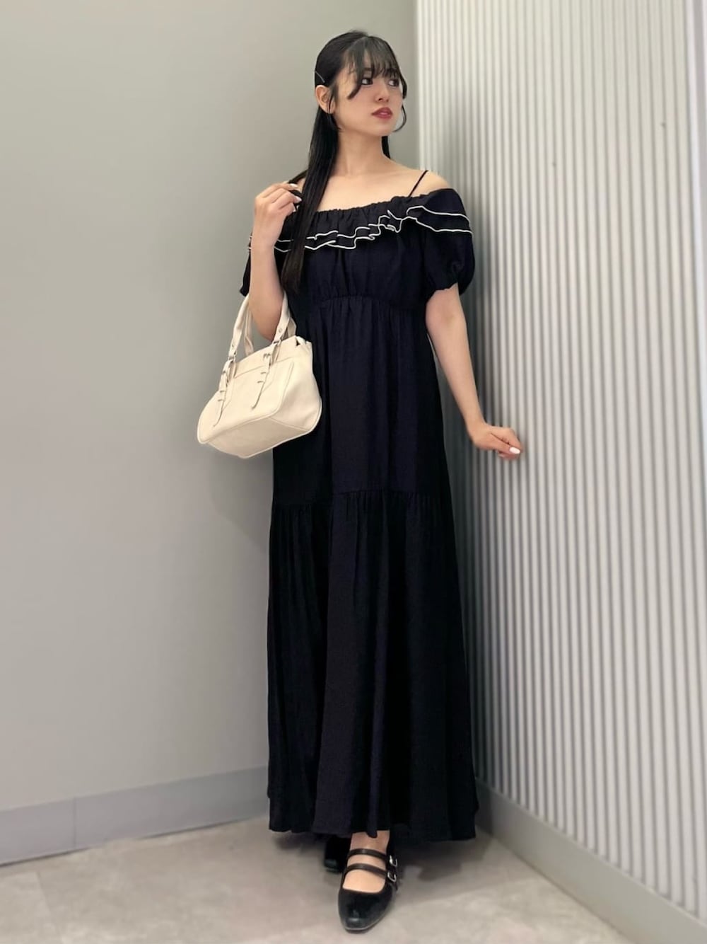 ホワイト系のショルダーバッグ、ブラック系のワンピース、ブラック系のパンプスを着用したレディースの夏コーディネートの1枚目の写真