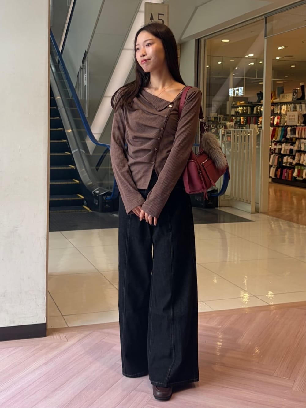 ブラック系のデニムパンツ、レッド系のショルダーバッグ、ブラウン系のTシャツ/カットソーを着用したレディースの秋コーディネートの1枚目の写真