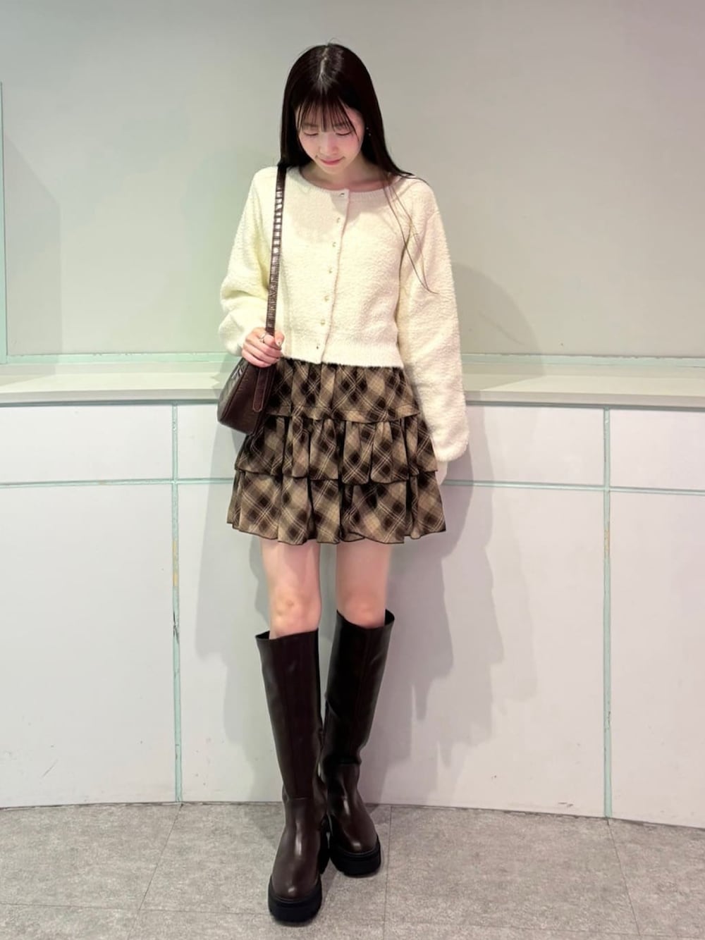 ホワイト系のカーディガン/ボレロ、ブラウン系のスカートを着用したレディースの秋コーディネートの1枚目の写真