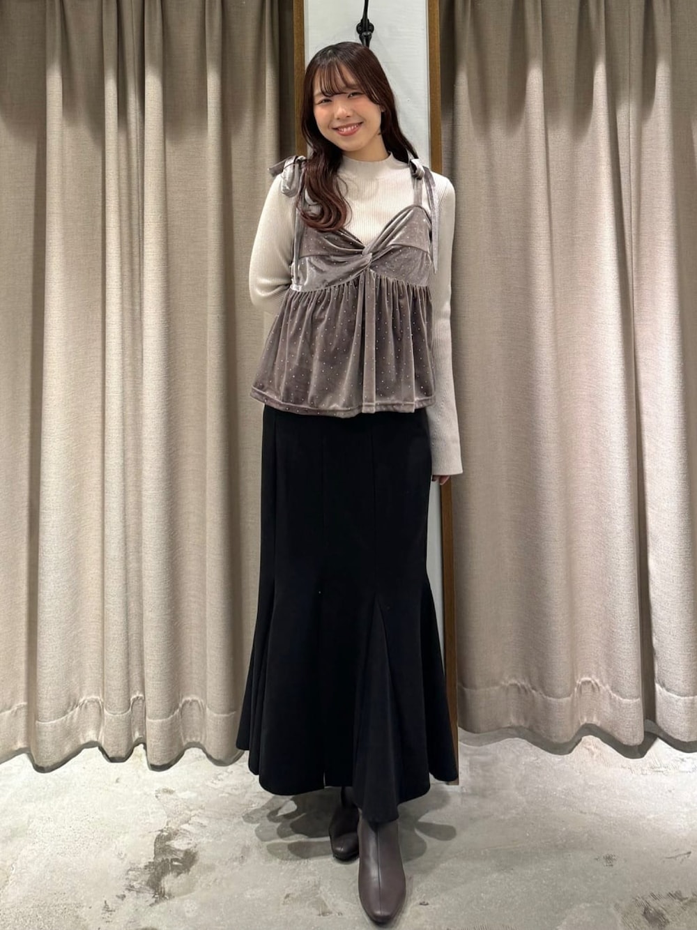 ピンク系のアンサンブル、ブラック系のスカートを着用したレディースの冬コーディネートの1枚目の写真