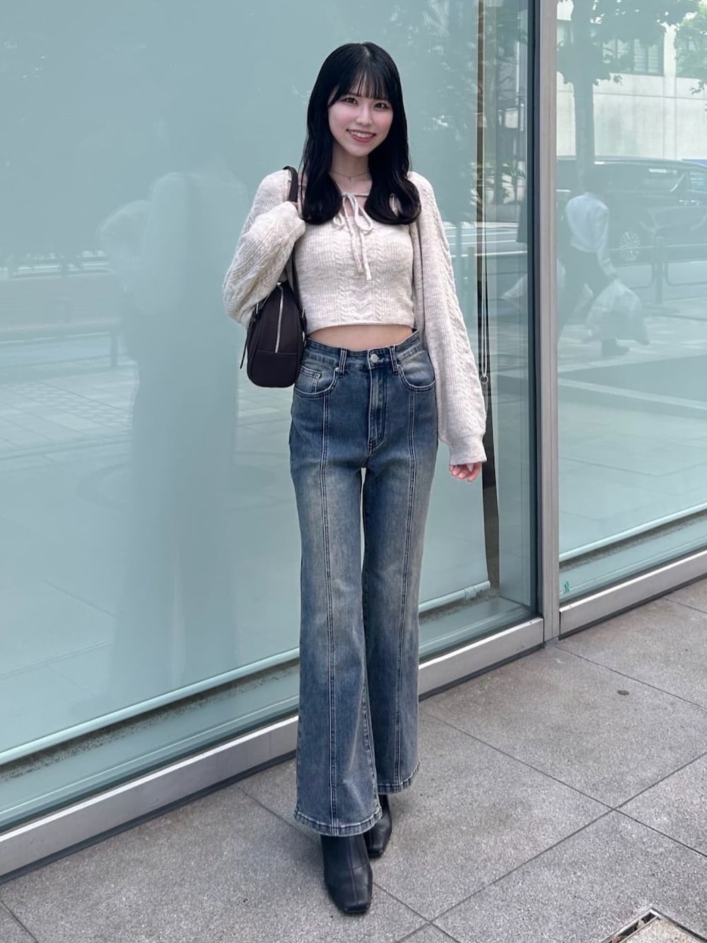ホワイト系のアンサンブル、ブルー系のデニムパンツ、ブラック系のブーツを着用したレディースの秋コーディネートの1枚目の写真
