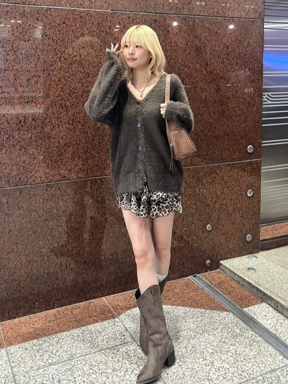 ブラウン系のニット/セーター、ブラウン系のスカート、ブラウン系のブーツを着用したレディースの秋コーディネートの1枚目の写真