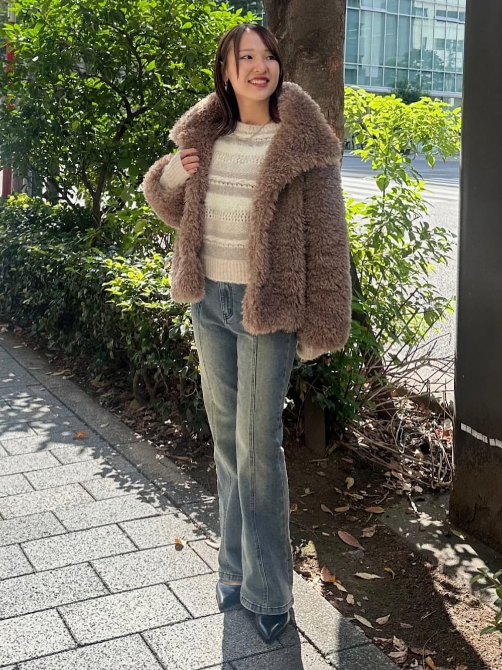 ブラウン系のブルゾン、ブルー系のデニムパンツ、ホワイト系のニット/セーターを着用したレディースの秋コーディネートの1枚目の写真