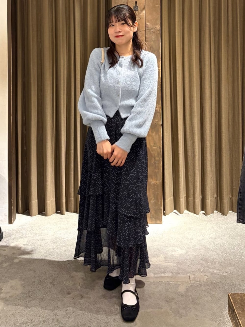 ブルー系のニット/セーター、ホワイト系のスカートを着用したレディースの秋コーディネートの1枚目の写真