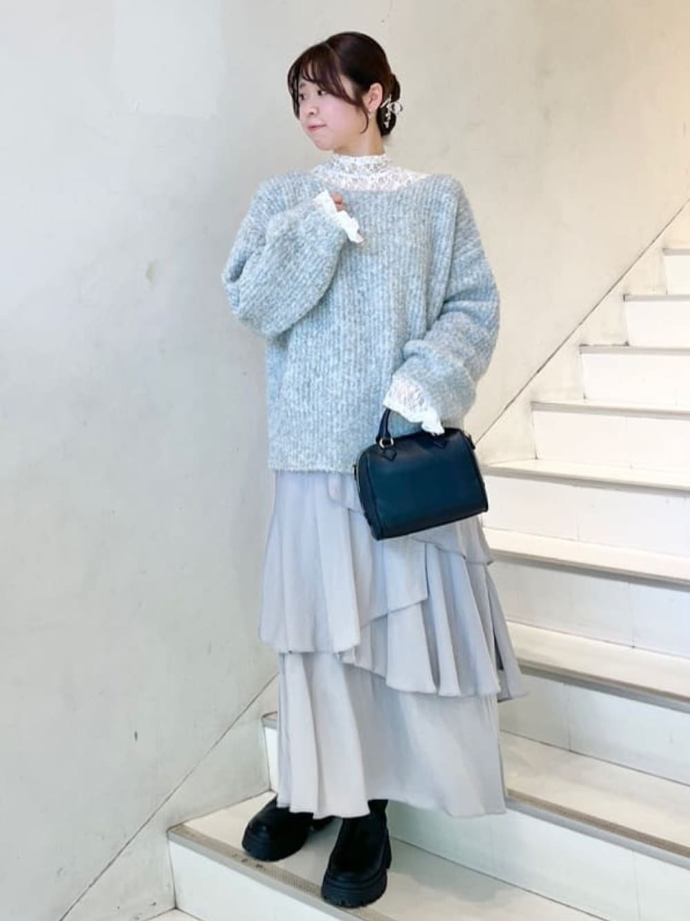 ブルー系のニット/セーター、ホワイト系のTシャツ/カットソー、グレー系のスカートを着用したレディースの冬コーディネートの1枚目の写真