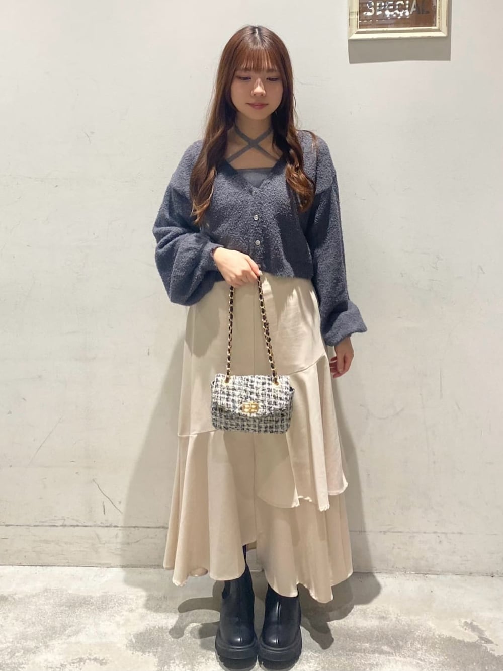 グレー系のニット/セーター、ホワイト系のショルダーバッグ、ホワイト系のスカートを着用したレディースの冬コーディネートの1枚目の写真