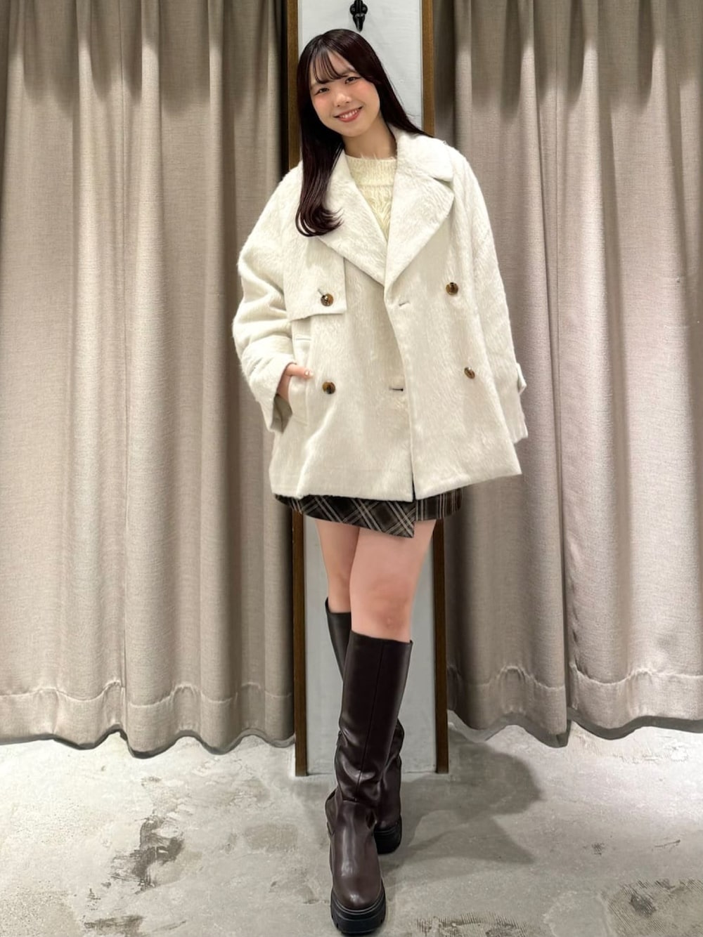 ホワイト系のチェスターコートを着用したレディースの冬コーディネートの1枚目の写真