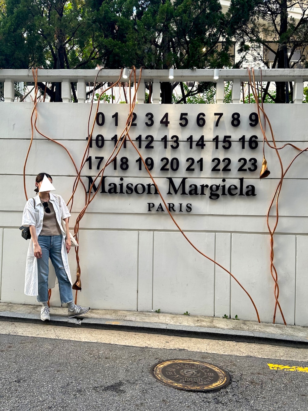 ブルー系のデニムパンツ、ホワイト系のワンピース、グレー系のスニーカーを着用したレディースの秋コーディネートの1枚目の写真