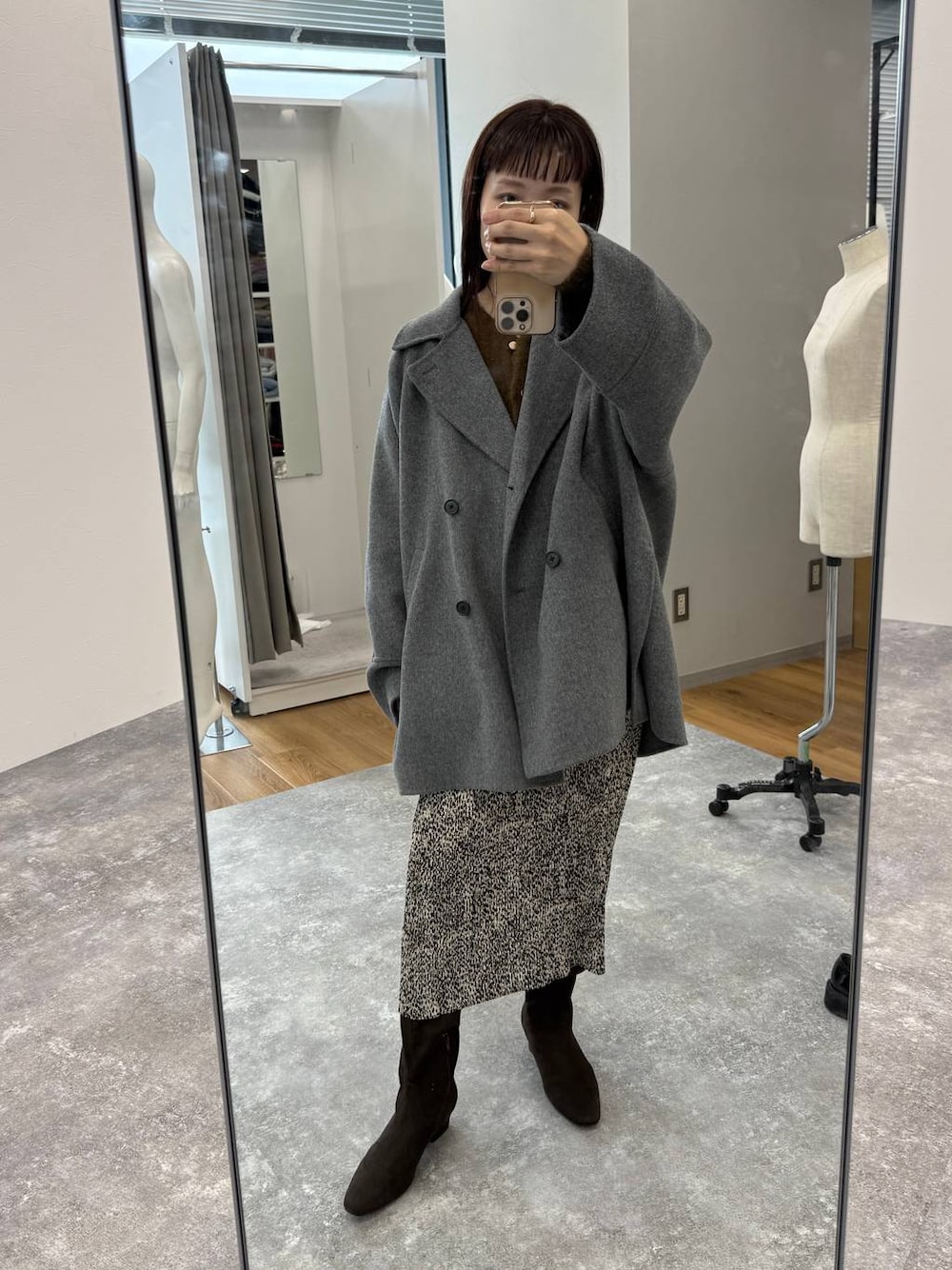 グレー系のその他アウター、ベージュ系のスカート、ブラウン系のブーツを着用したレディースの秋コーディネートの1枚目の写真