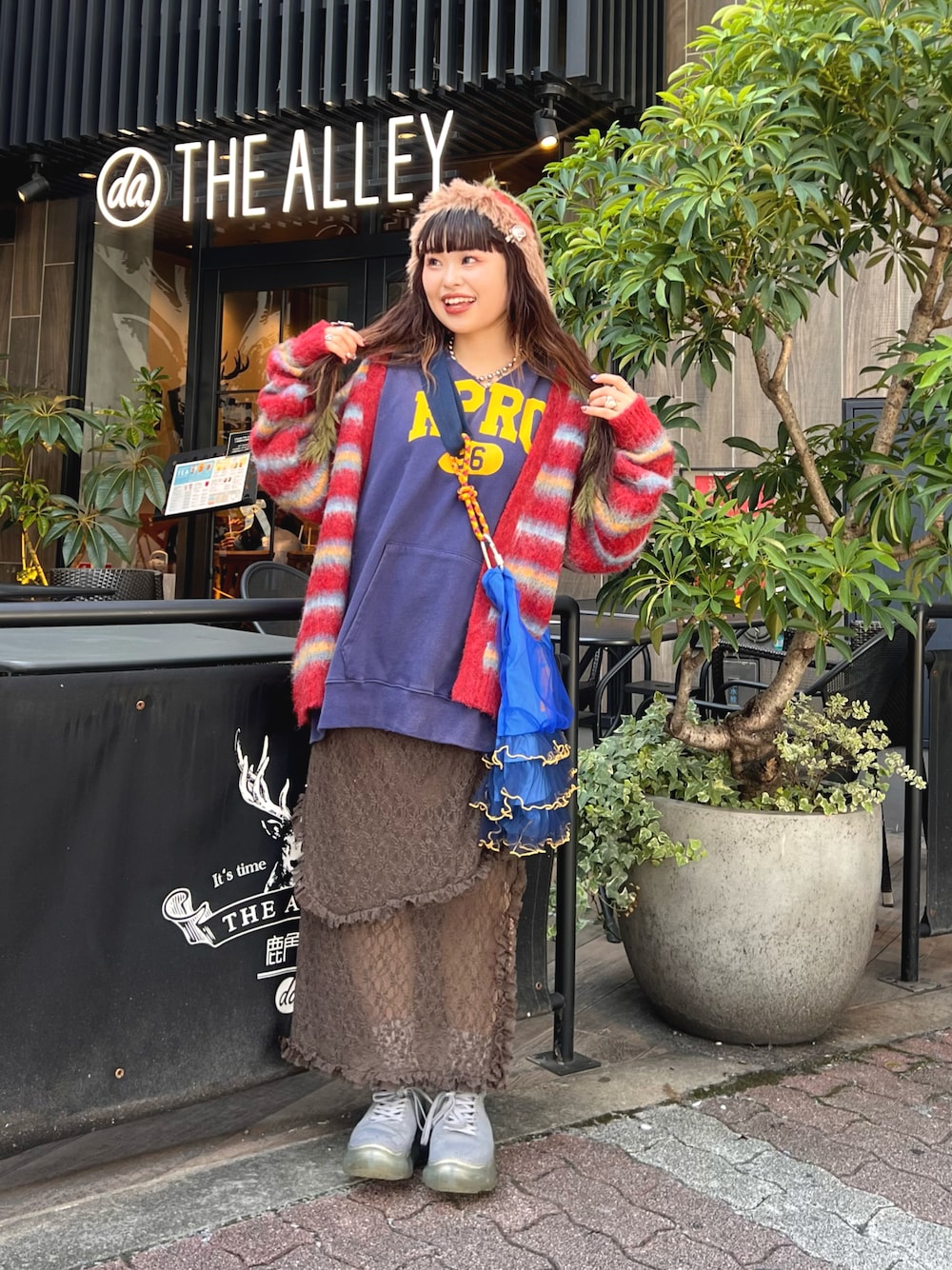 ブラック系のパーカー、レッド系のカーディガン/ボレロ、ブラウン系のスカートを着用したレディースの秋コーディネートの1枚目の写真