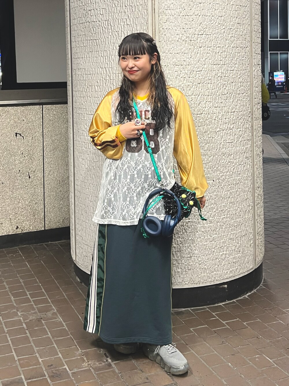 グリーン系のスカート、ブラック系のショルダーバッグ、イエロー系のTシャツ/カットソーを着用したレディースの冬コーディネートの1枚目の写真