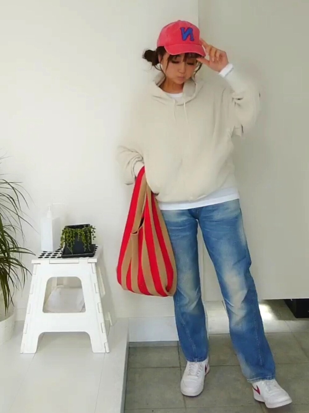 ベージュ系のカーディガン/ボレロ、ブルー系のデニムパンツ、レッド系のトートバッグを着用したレディースの春コーディネートの2枚目の写真