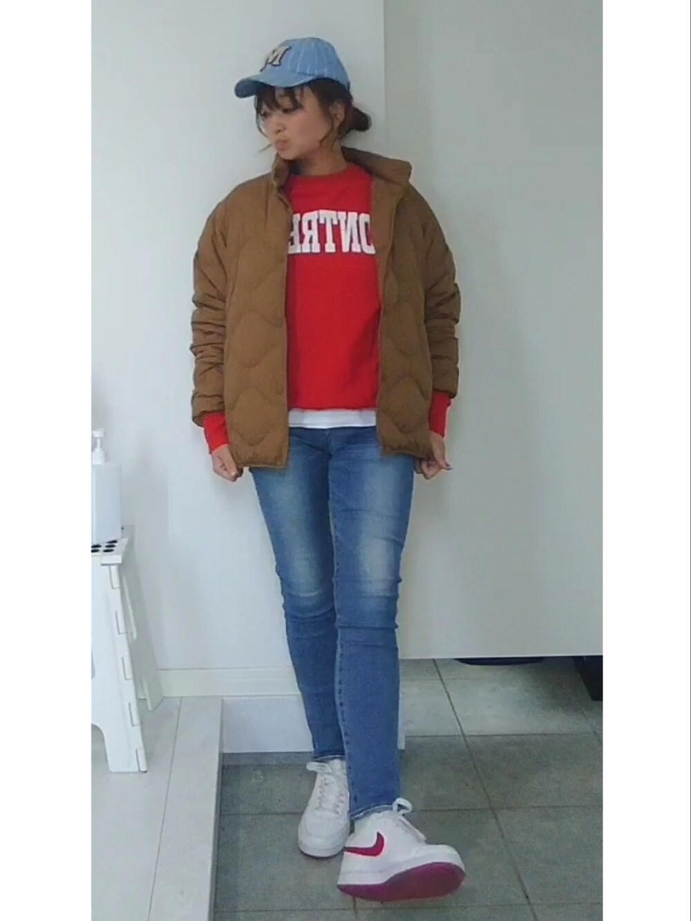 ブルー系のデニムパンツ、オレンジ系のスウェット、レッド系のスニーカーを着用したレディースの冬コーディネートの2枚目の写真