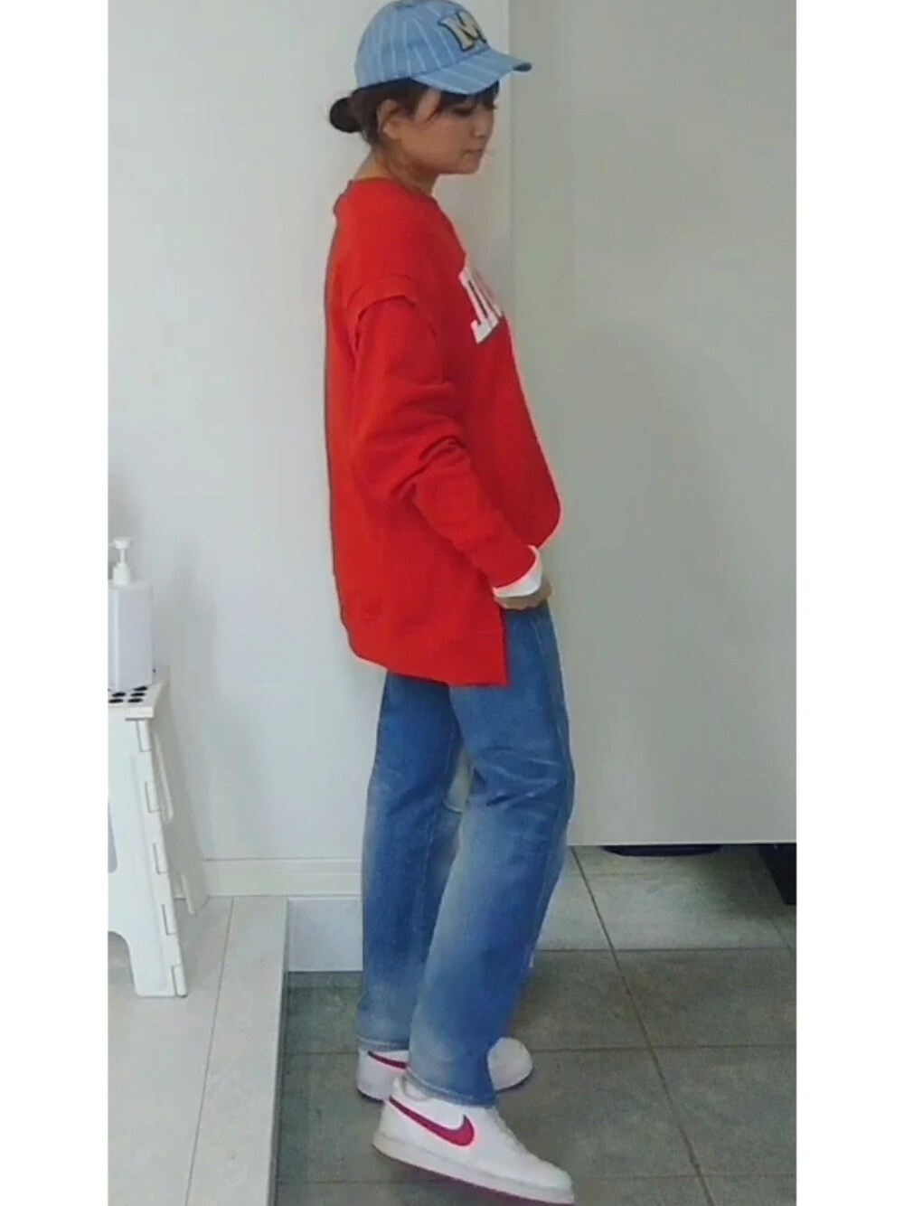 ブルー系のデニムパンツ、オレンジ系のスウェット、レッド系のスニーカーを着用したレディースの冬コーディネートの3枚目の写真