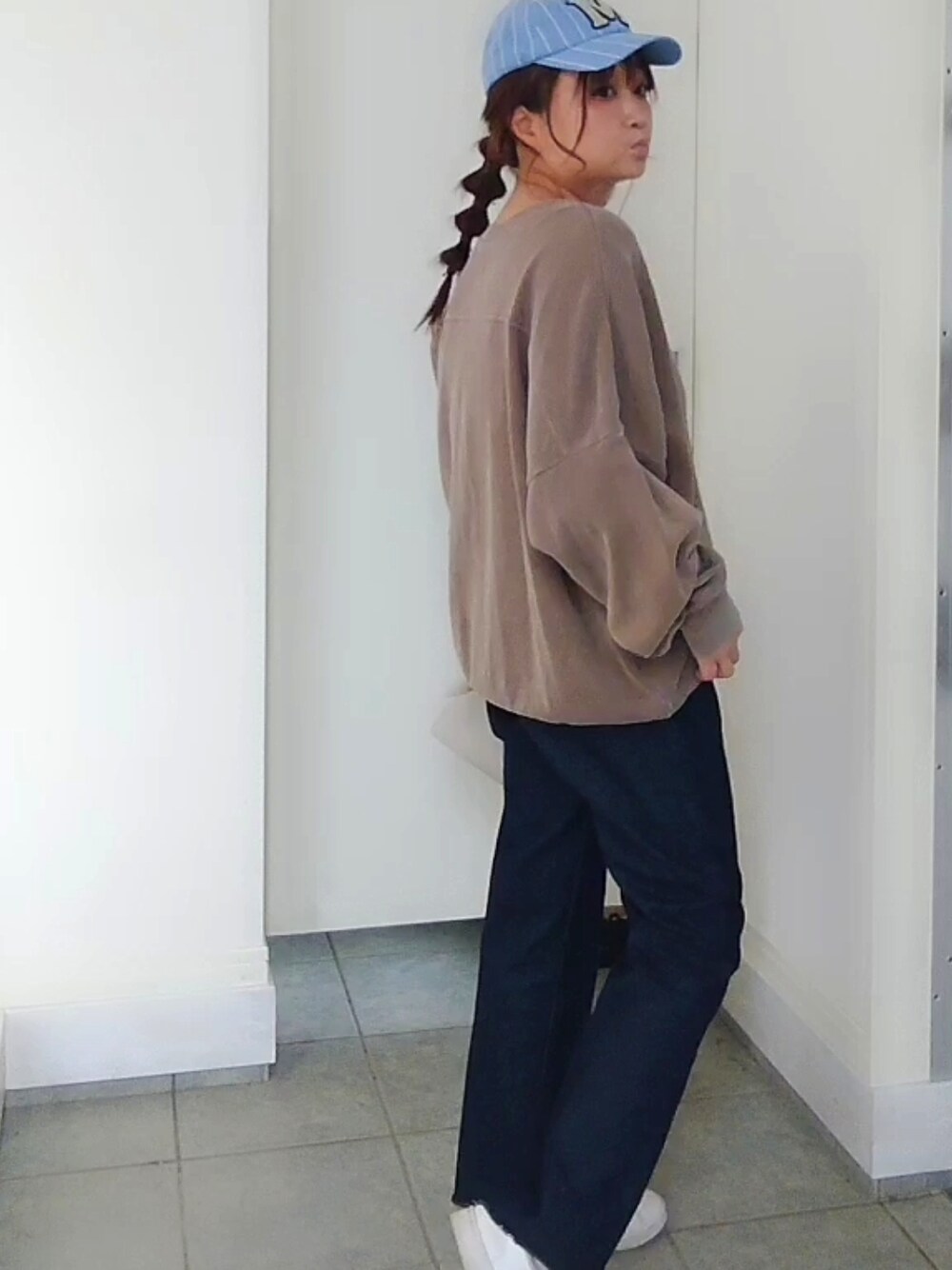 ブルー系のデニムパンツ、ブラウン系のスウェット、ホワイト系のクラッチバッグを着用したレディースの春コーディネートの2枚目の写真