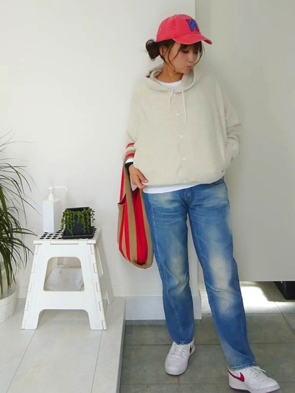 ベージュ系のカーディガン/ボレロ、ブルー系のデニムパンツ、レッド系のトートバッグを着用したレディースの春コーディネートの3枚目の写真