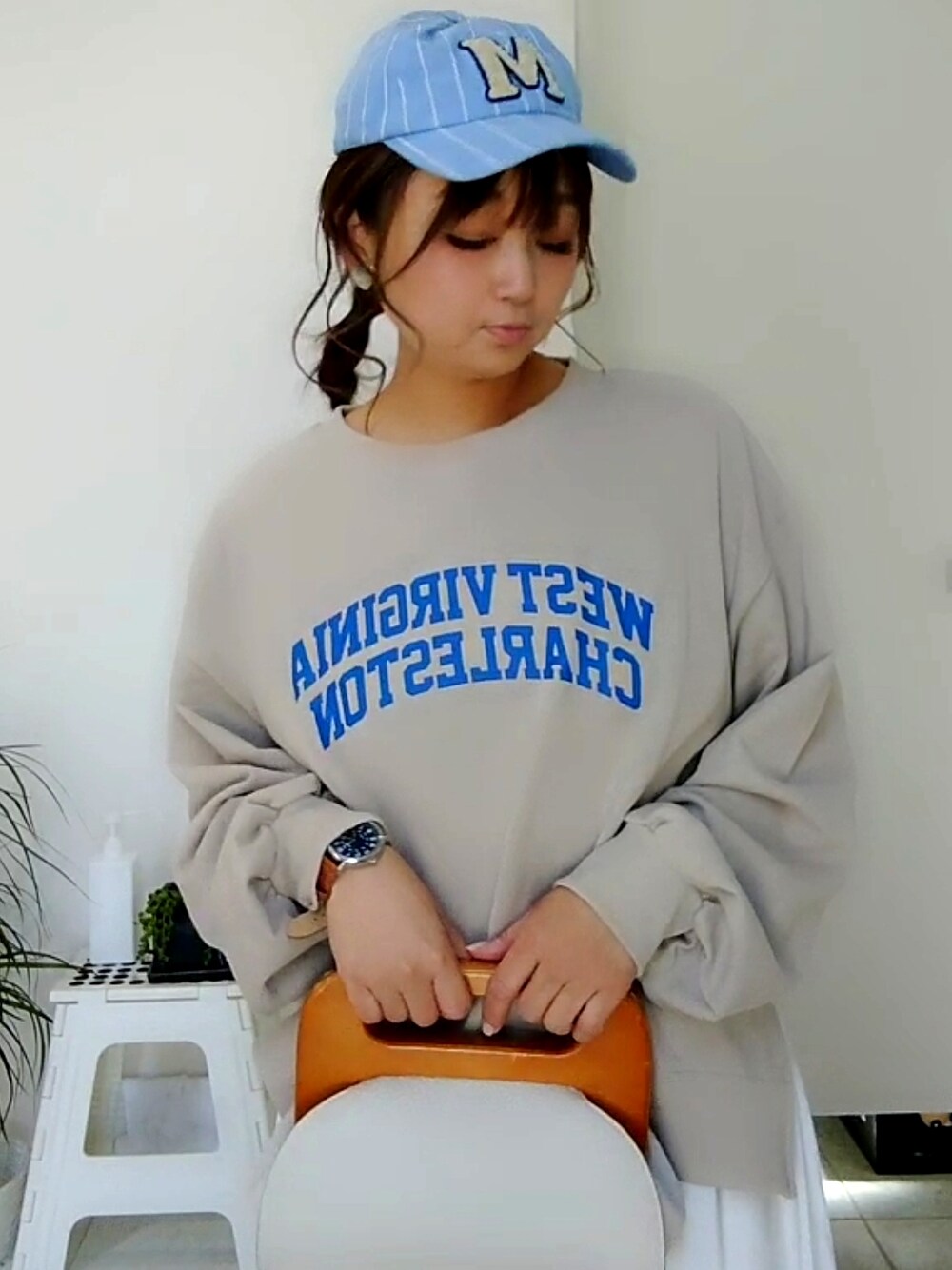 グレー系のスウェット、ホワイト系のクラッチバッグ、ブルー系のスニーカーを着用したレディースの春コーディネートの4枚目の写真
