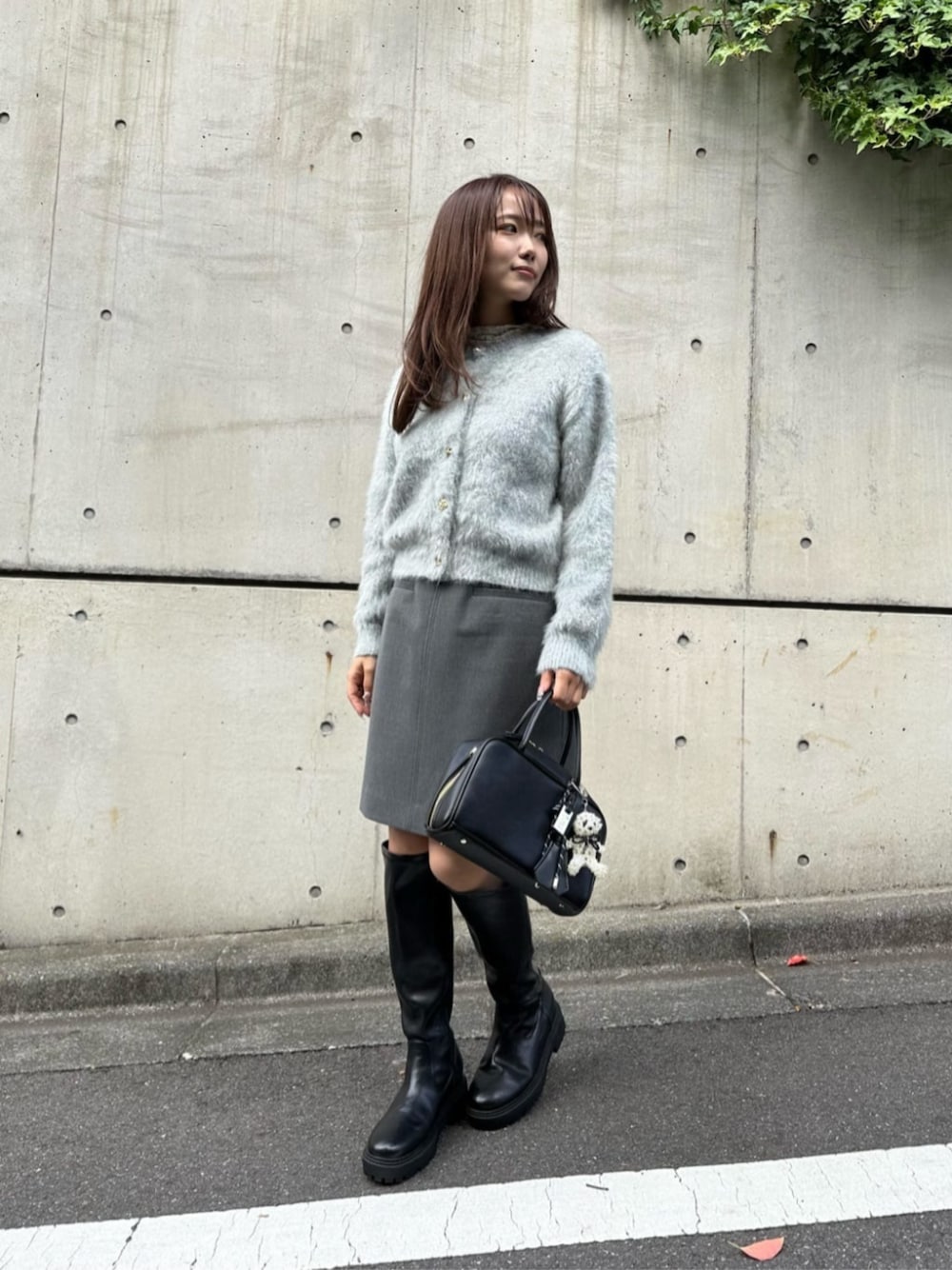 ブラック系のボストンバッグ、ブラック系のブーツ、グリーン系のカーディガン/ボレロを着用したレディースの秋コーディネートの1枚目の写真