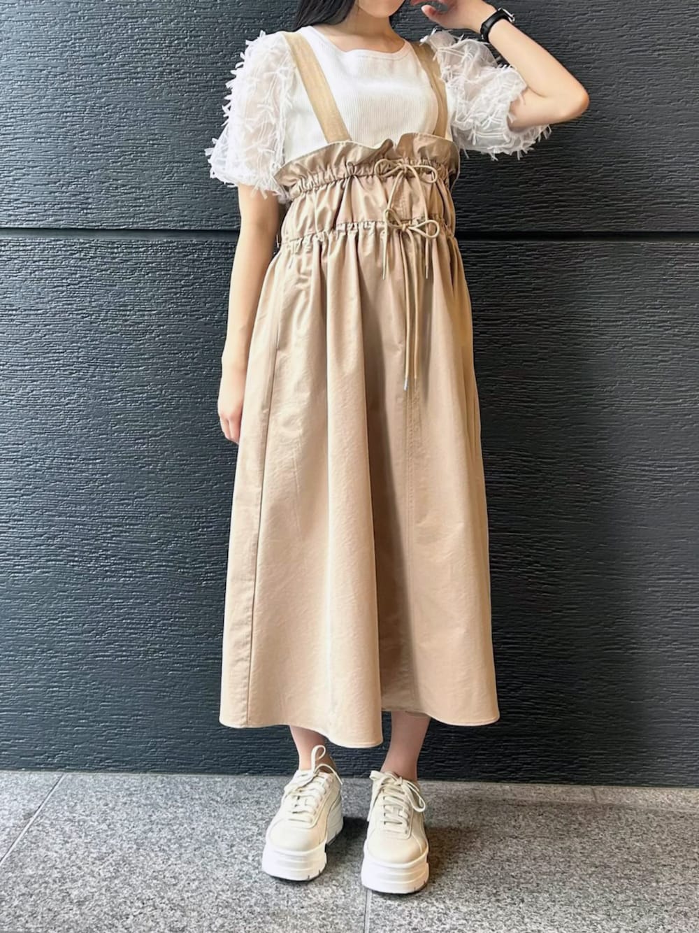 ベージュ系のジャンパースカート、ホワイト系のニット/セーターを着用したレディースの冬コーディネートの1枚目の写真