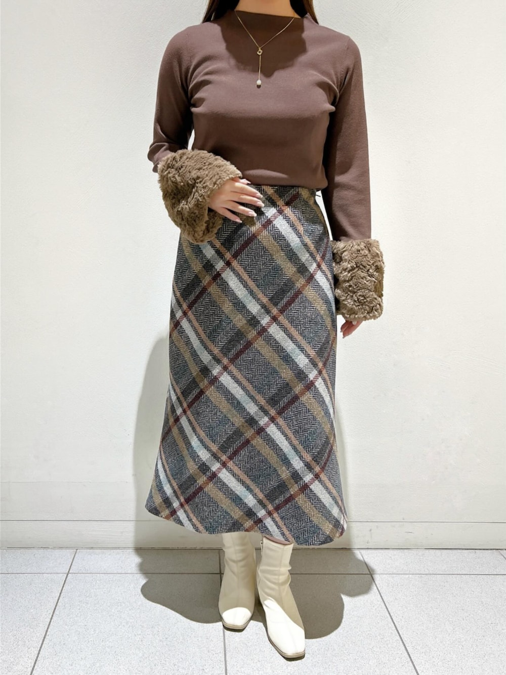 ブラウン系のニット/セーター、ブルー系のスカートを着用したレディースの秋コーディネートの1枚目の写真