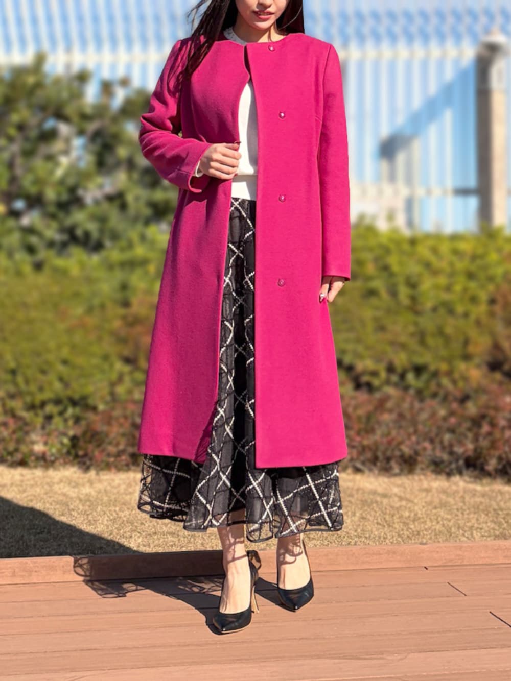 グレー系のスカート、ホワイト系のノーカラーコート、ホワイト系のニット/セーターを着用したレディースの冬コーディネートの1枚目の写真