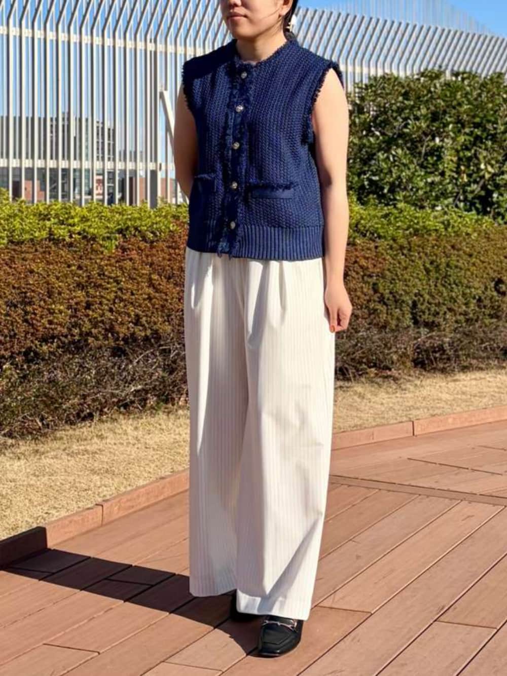 ブルー系のベスト、ホワイト系のその他パンツを着用したレディースの春コーディネートの1枚目の写真