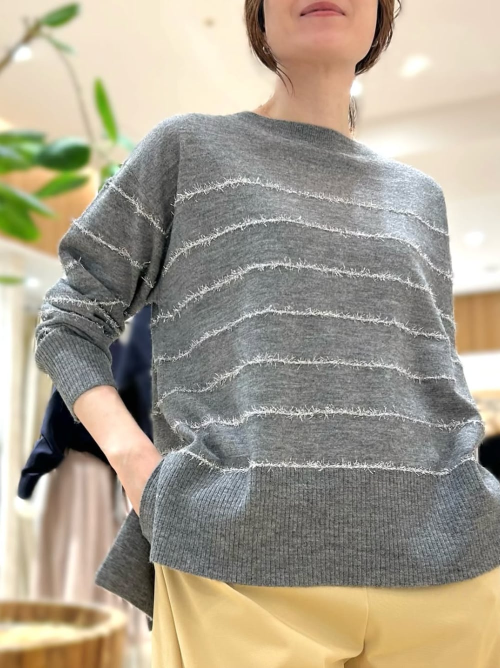 イエロー系のスラックス、グレー系のニット/セーターを着用したレディースの秋コーディネートの1枚目の写真