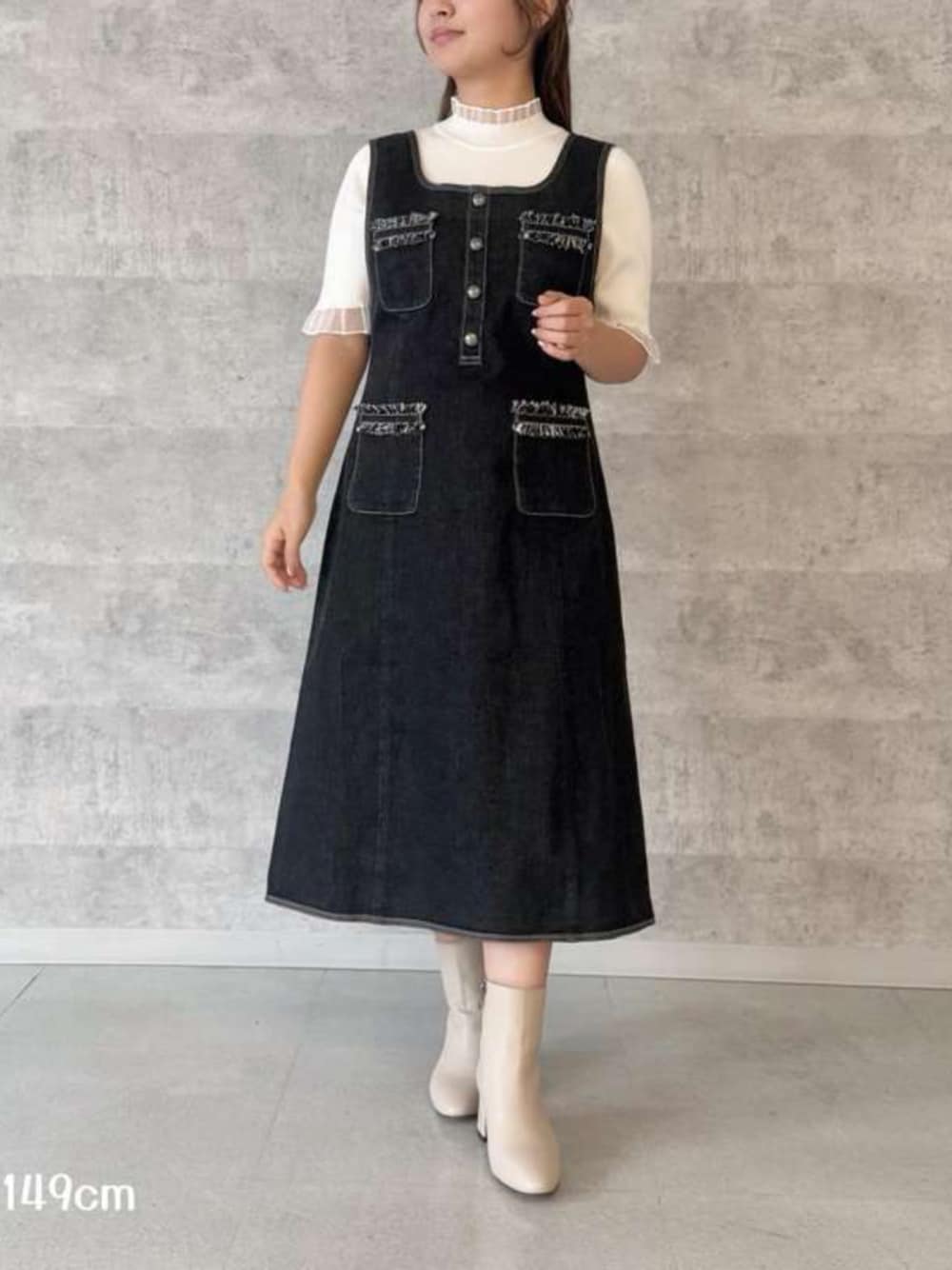 ブルー系のジャンパースカート、ホワイト系のニット/セーターを着用したレディースの春コーディネートの1枚目の写真