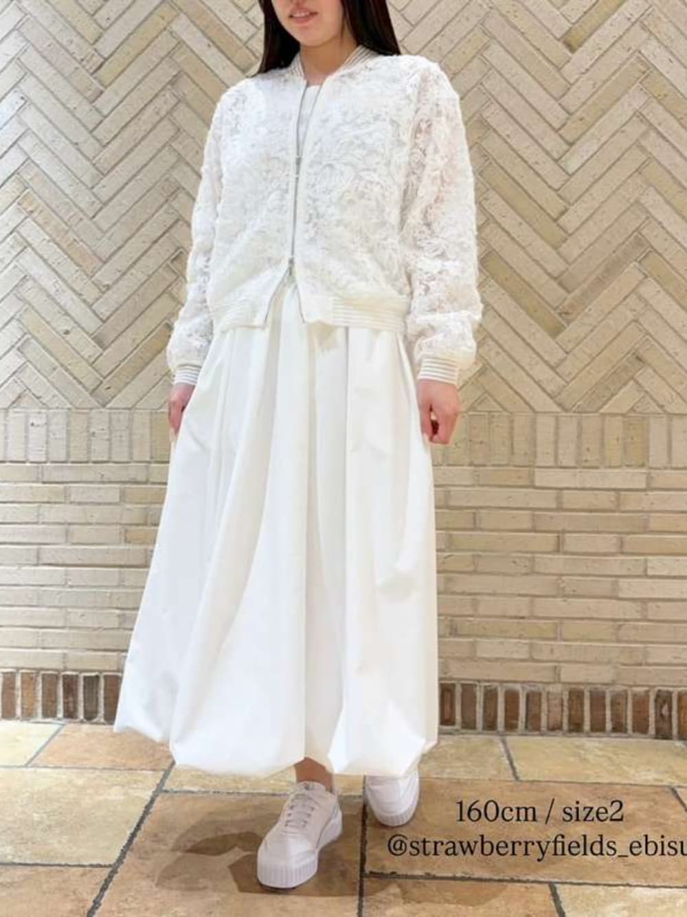 ホワイト系のスカート、ホワイト系のブルゾンを着用したレディースの春コーディネートの1枚目の写真