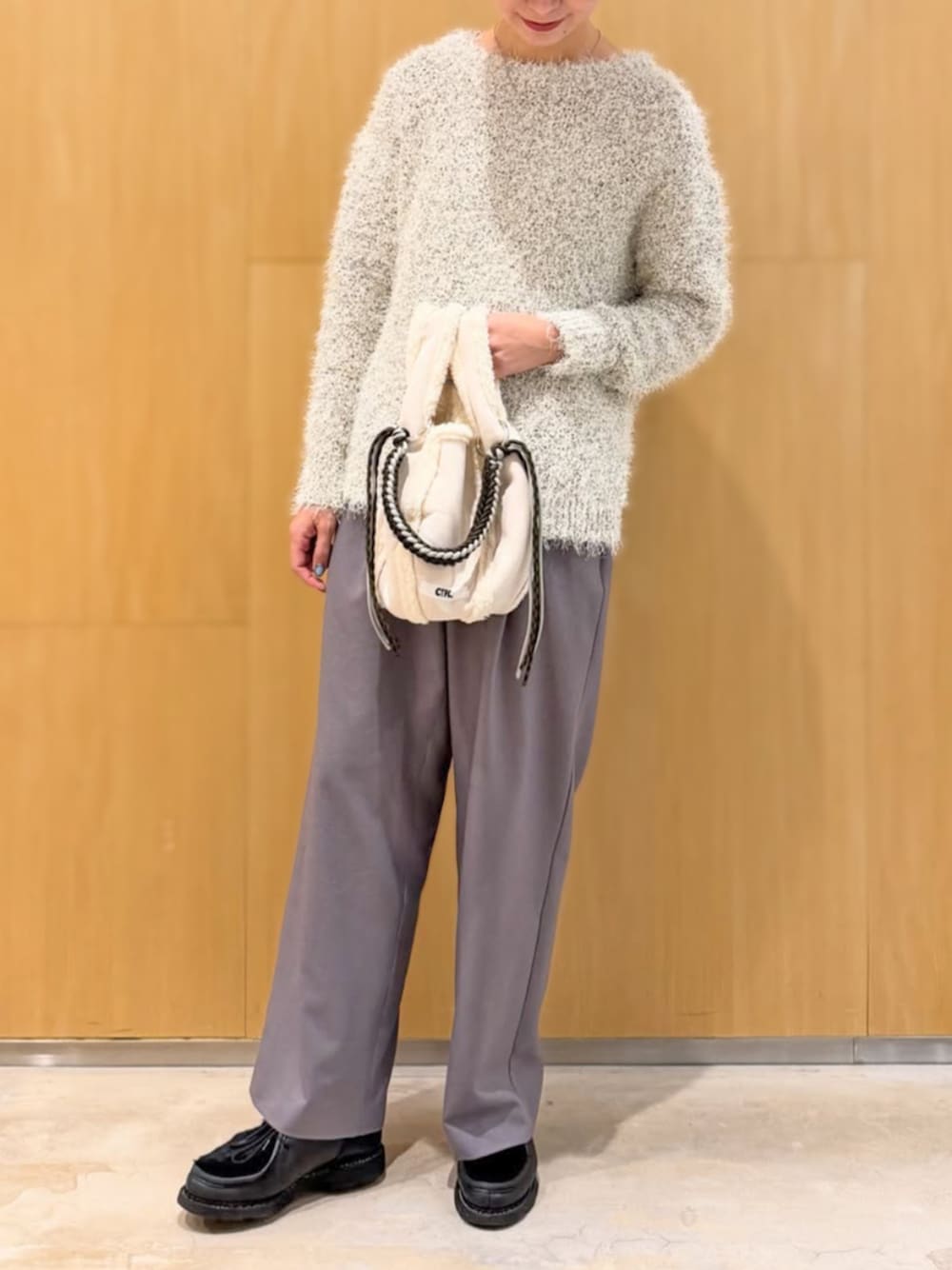 グレー系のスラックス、ホワイト系のニット/セーターを着用したレディースの冬コーディネートの1枚目の写真