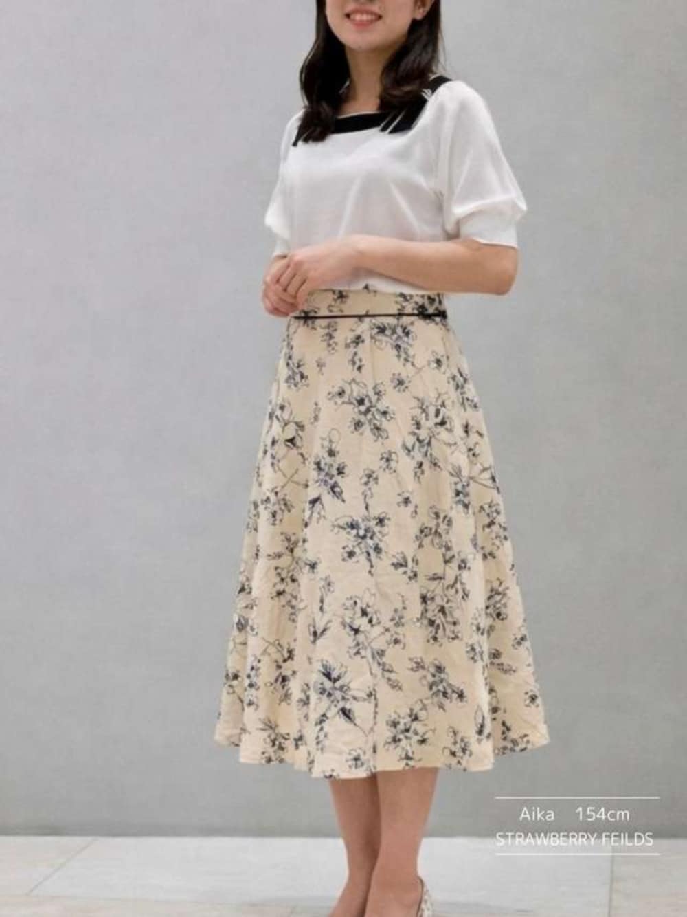 ホワイト系のニット/セーター、ベージュ系のスカートを着用したレディースの春コーディネートの1枚目の写真