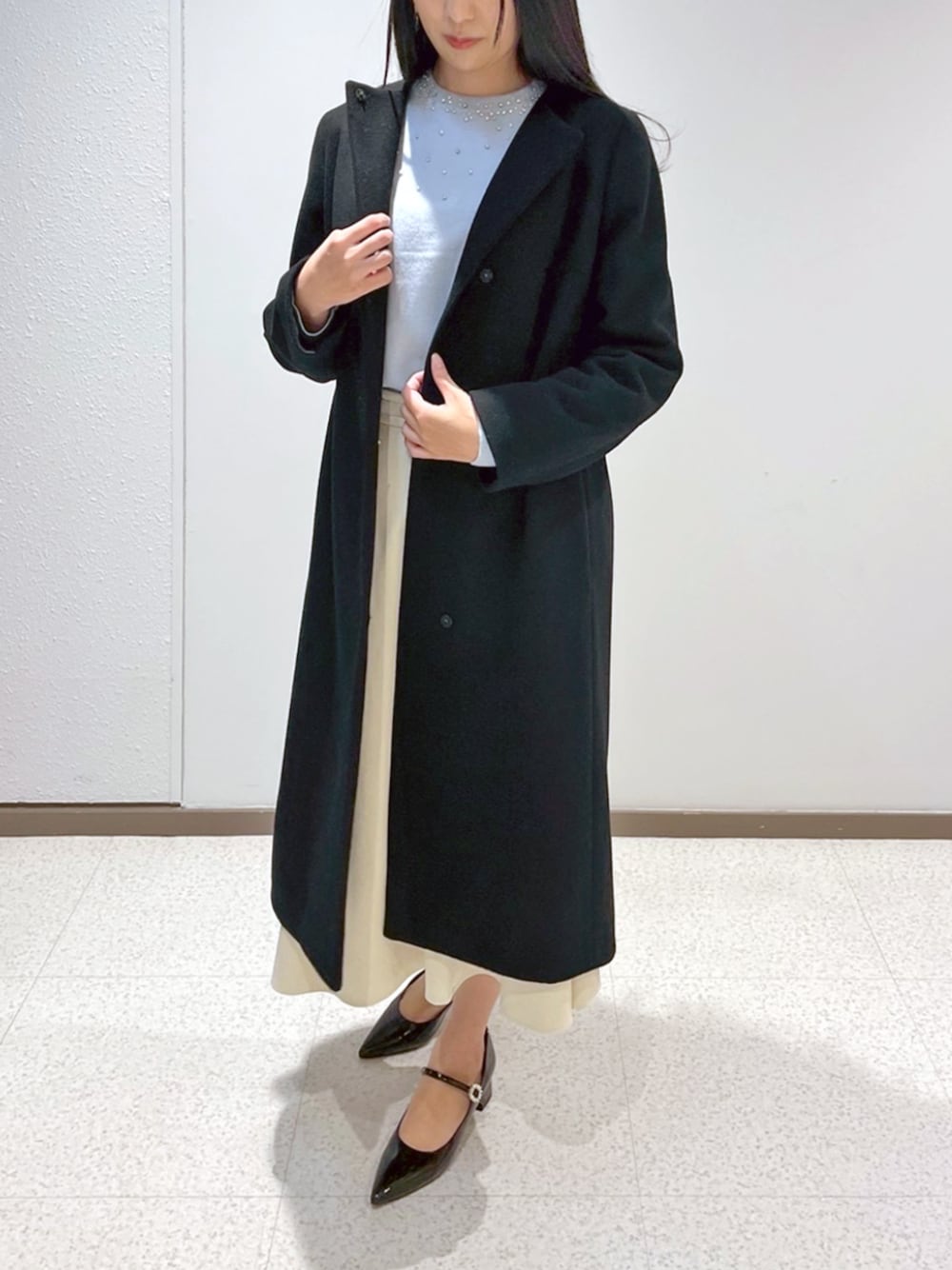 ホワイト系のノーカラーコート、ホワイト系のニット/セーターを着用したレディースの冬コーディネートの1枚目の写真