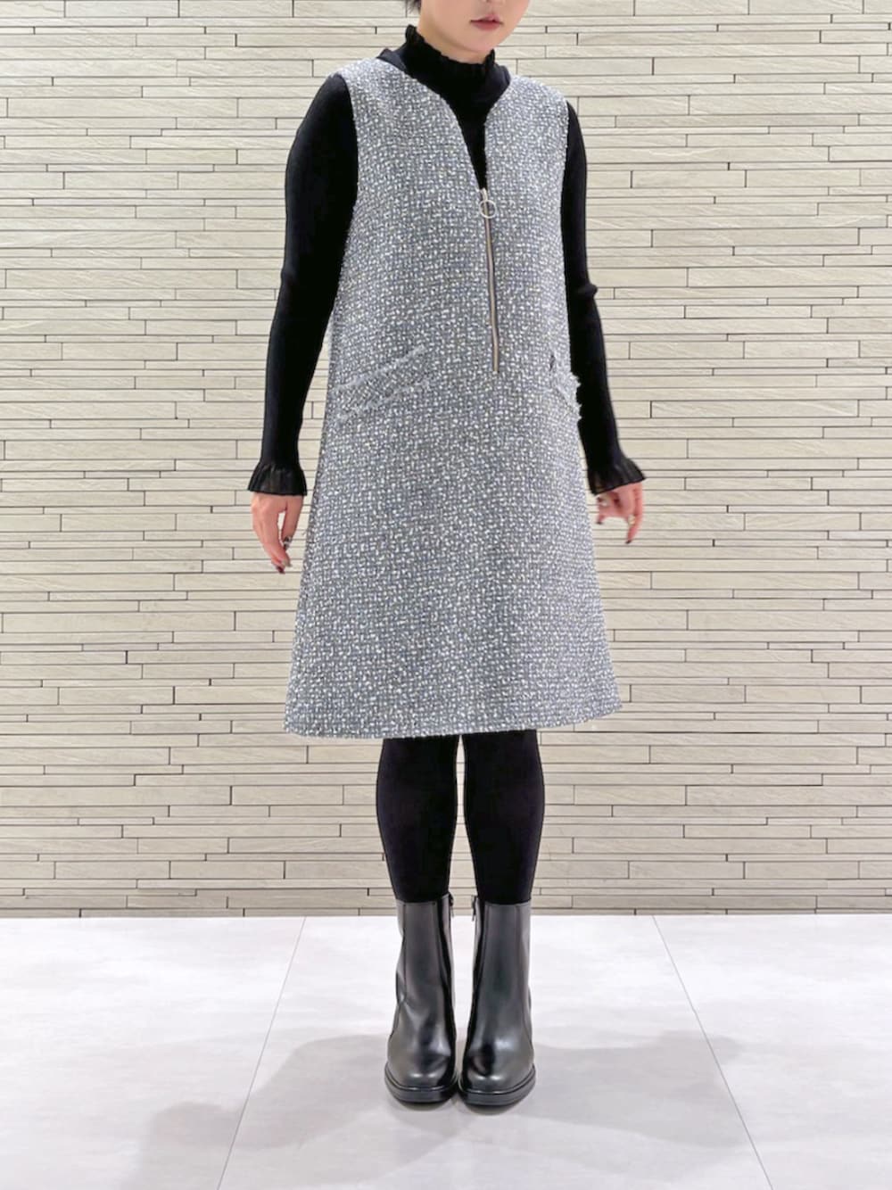 グレー系のジャンパースカート、ブラック系のニット/セーターを着用したレディースの冬コーディネートの1枚目の写真