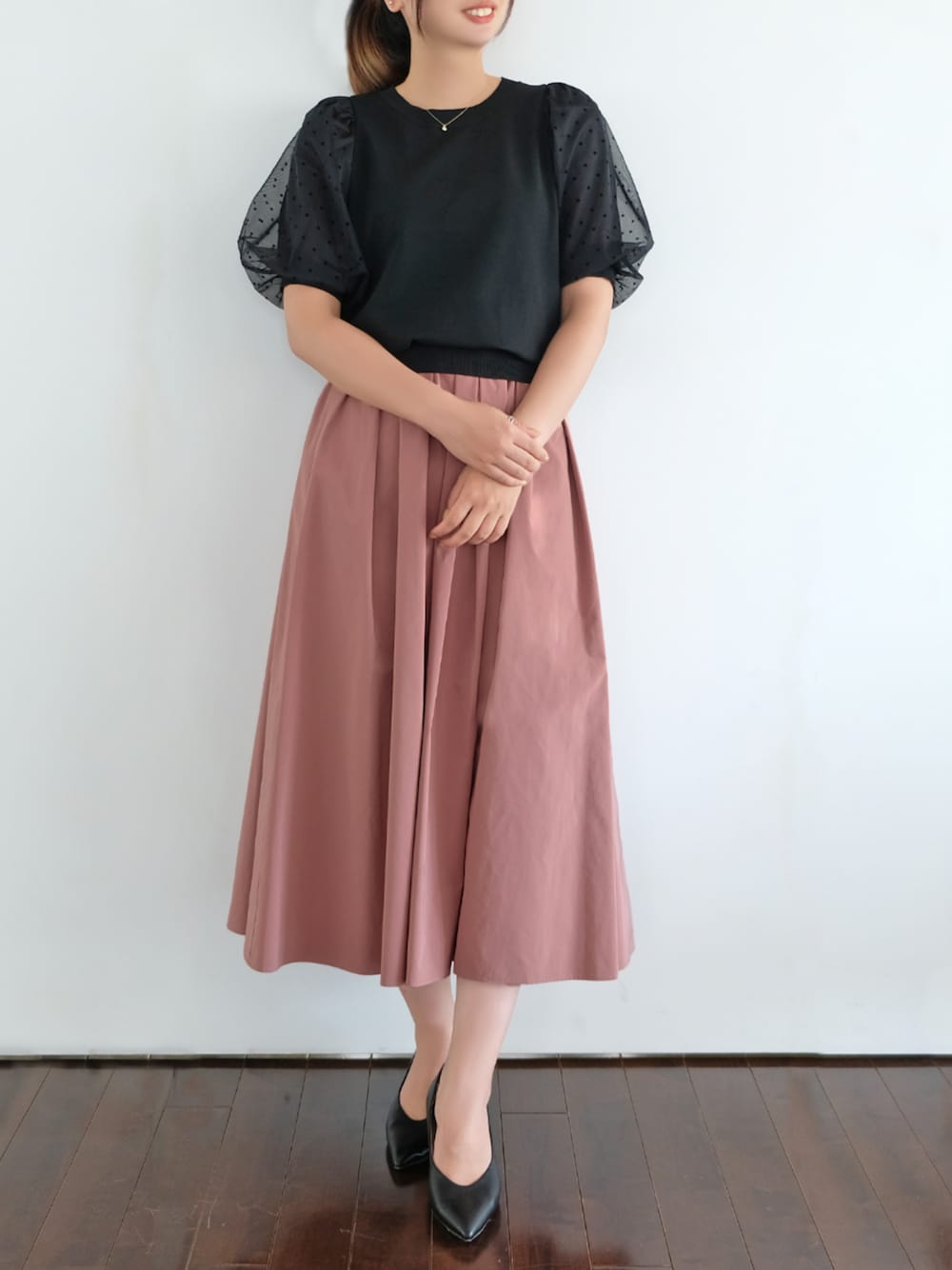 ブラック系のニット/セーター、ピンク系のスカートを着用したレディースの秋コーディネートの1枚目の写真