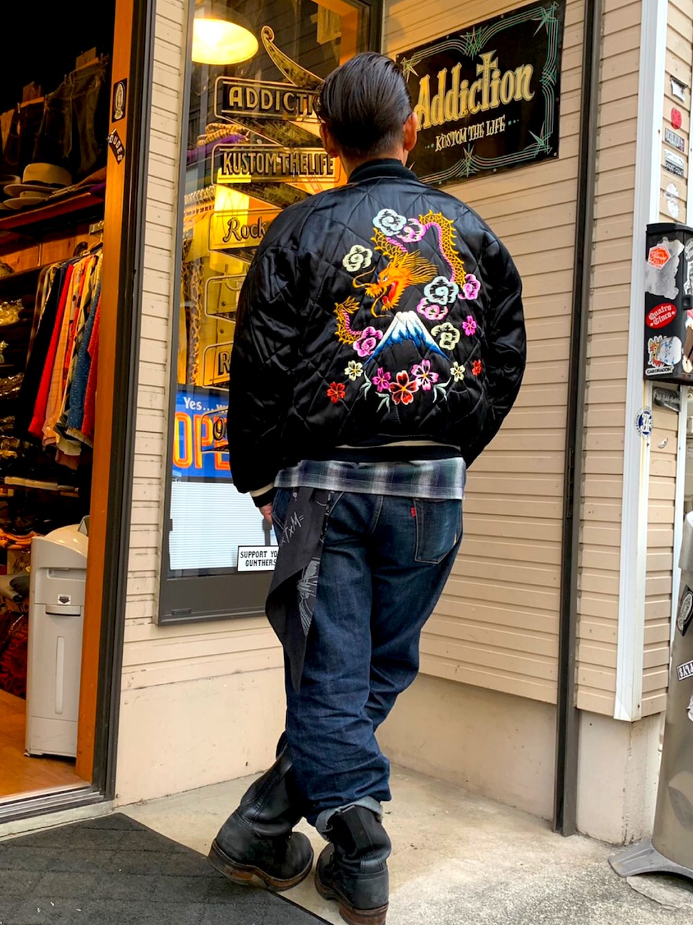 ブルー系のデニムパンツ、ブラック系のブーツ、その他のスカジャンを着用したメンズの秋コーディネートの1枚目の写真