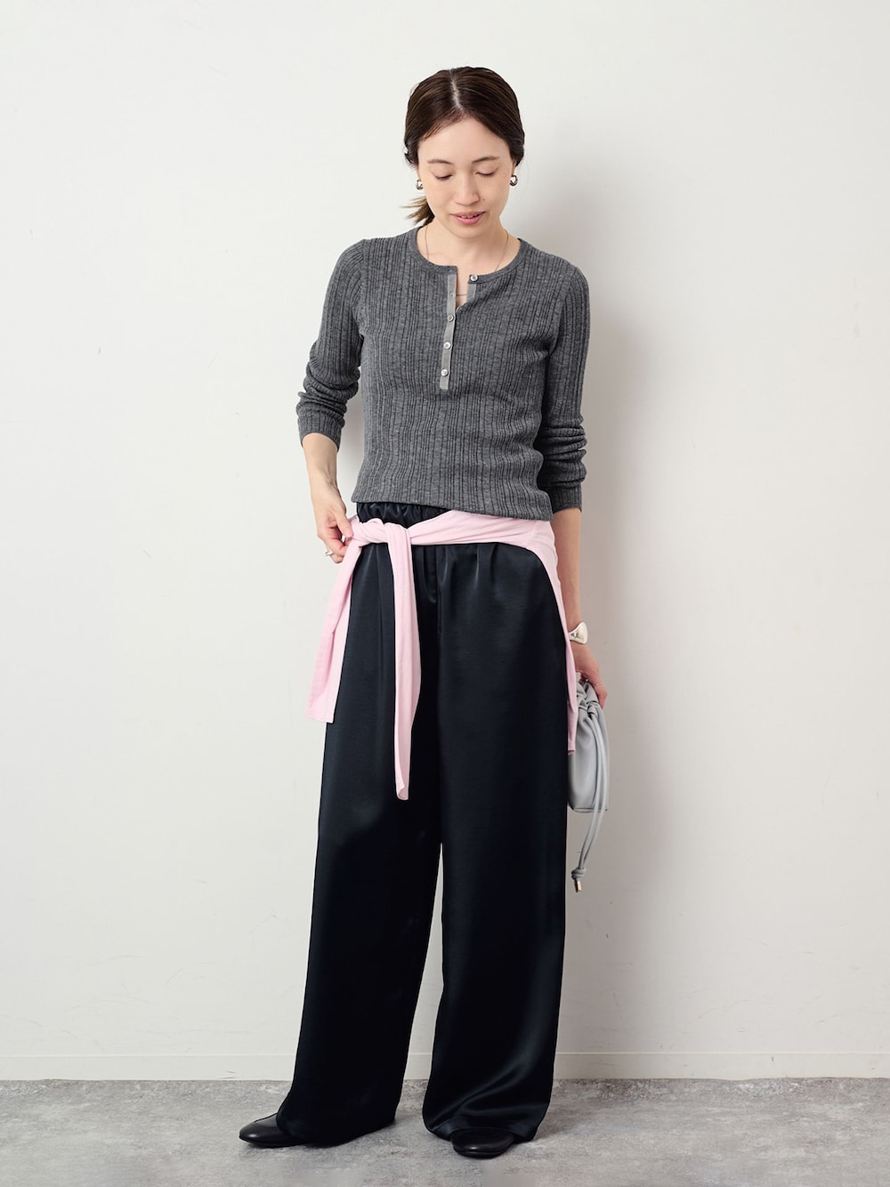 ブラック系のその他パンツ、グレー系のニット/セーター、ブルー系のクラッチバッグを着用したレディースの夏コーディネートの1枚目の写真