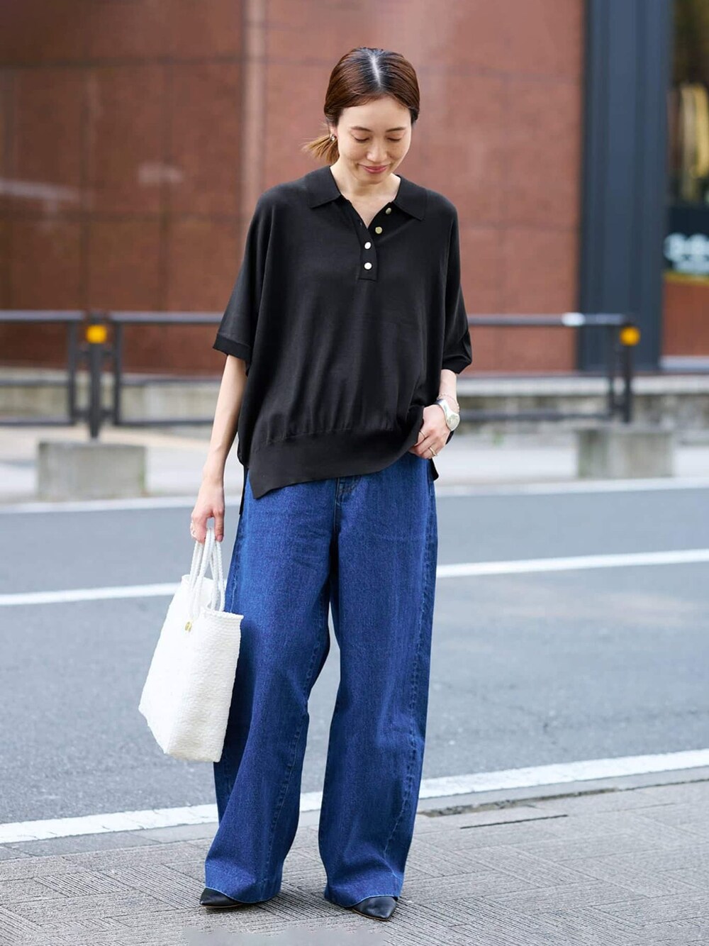 ブルー系のデニムパンツ、ブラック系のニット/セーター、ホワイト系のトートバッグを着用したレディースの夏コーディネートの1枚目の写真
