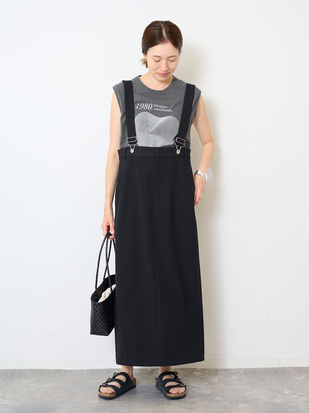 ブラック系のスカート、グレー系のTシャツ/カットソー、ブラック系のかごバッグを着用したレディースの夏コーディネートの1枚目の写真