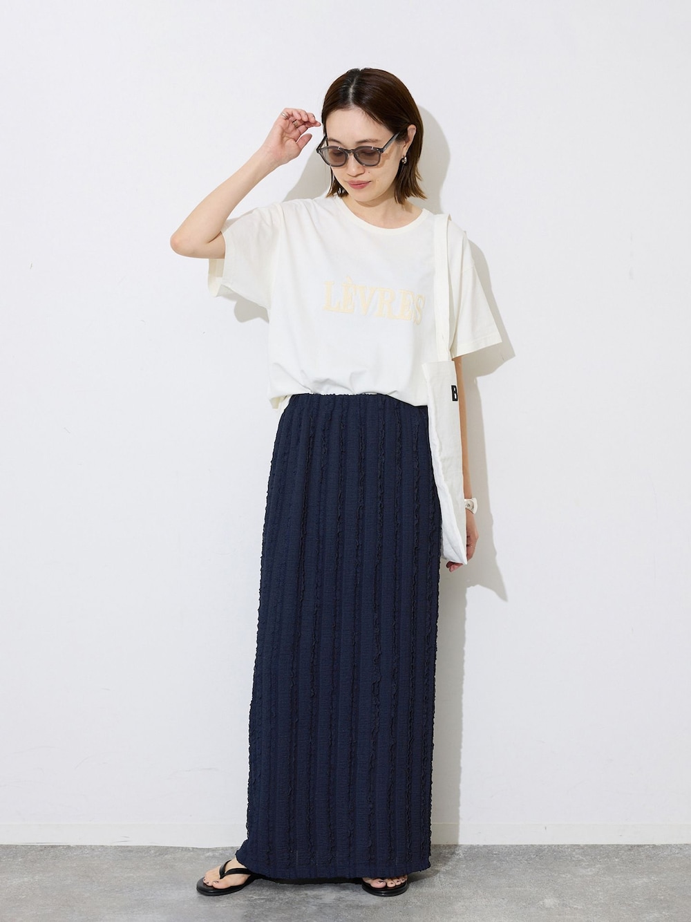 ブルー系のスカート、ホワイト系のTシャツ/カットソー、オレンジ系のトートバッグを着用したレディースの春コーディネートの1枚目の写真