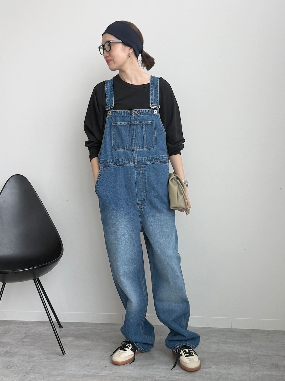 ブラック系のTシャツ/カットソー、ベージュ系のクラッチバッグ、ホワイト系のスニーカーを着用したレディースの冬コーディネートの1枚目の写真