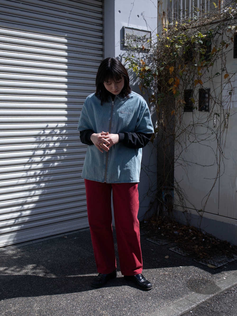 レッド系のデニムパンツ、ブルー系のシャツ/ブラウス、ブラック系のTシャツ/カットソーを着用したレディースの春コーディネートの1枚目の写真