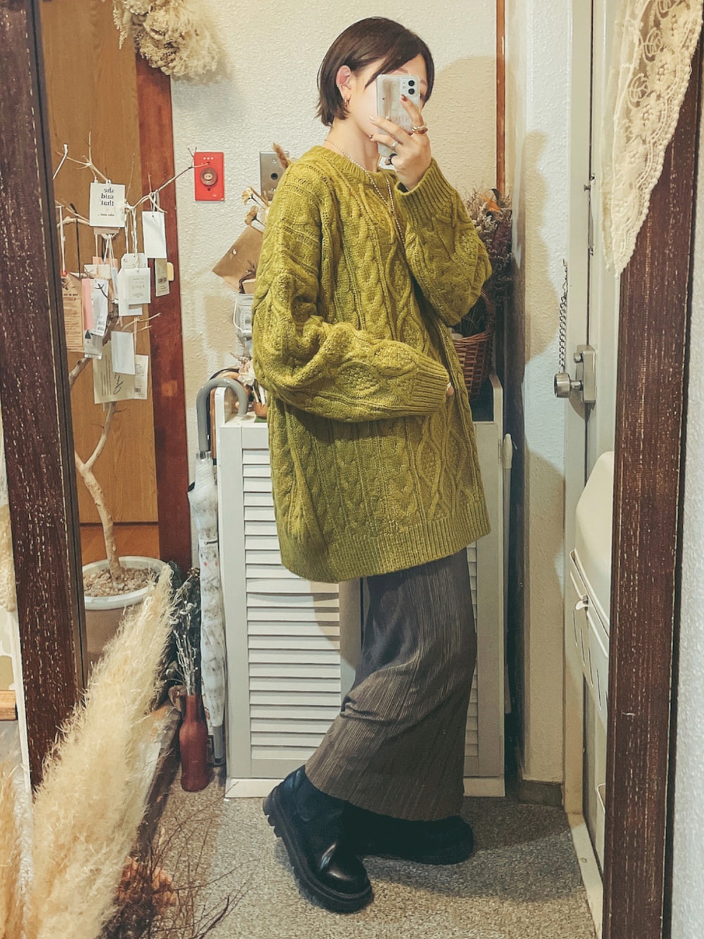 グリーン系のニット/セーター、ブラック系のブーツ、ブラウン系のスカートを着用したレディースの秋コーディネートの1枚目の写真